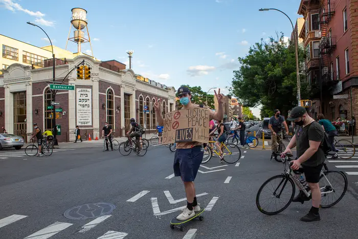 A man holds a Black Lives Matter sign while on a skateboard